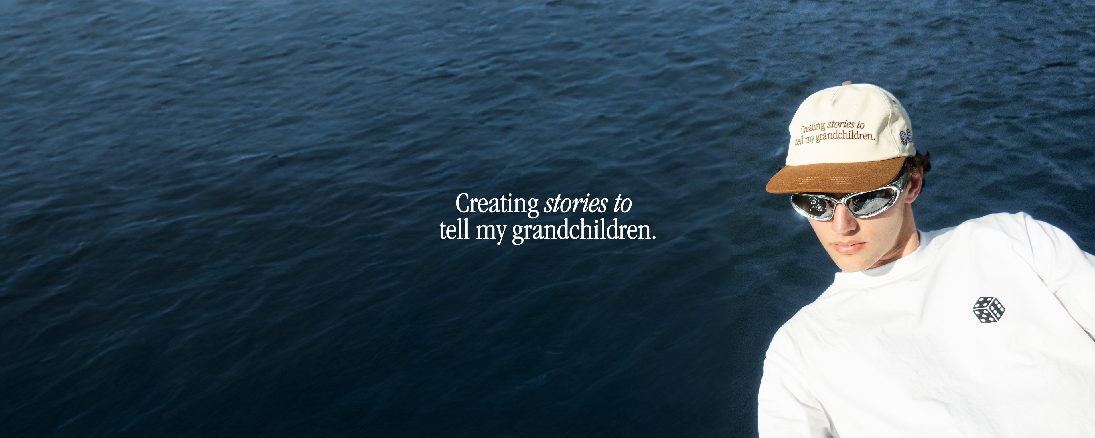 Person wearing a cap and sunglasses with text 'Creating stories to tell my grandchildren' over a blue water background
